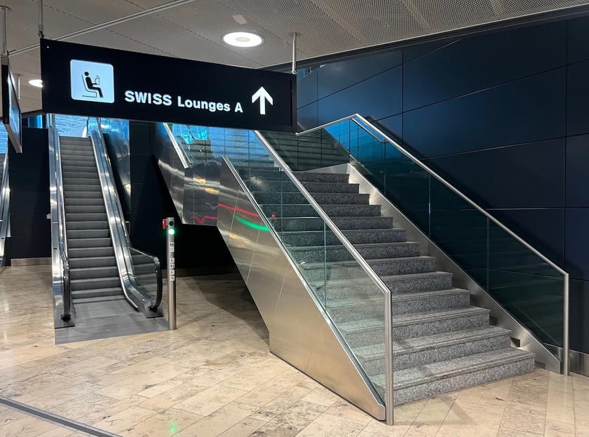 Signage directing passengers to the SWISS Lounges on the upper level of Zurich Airport Terminal A