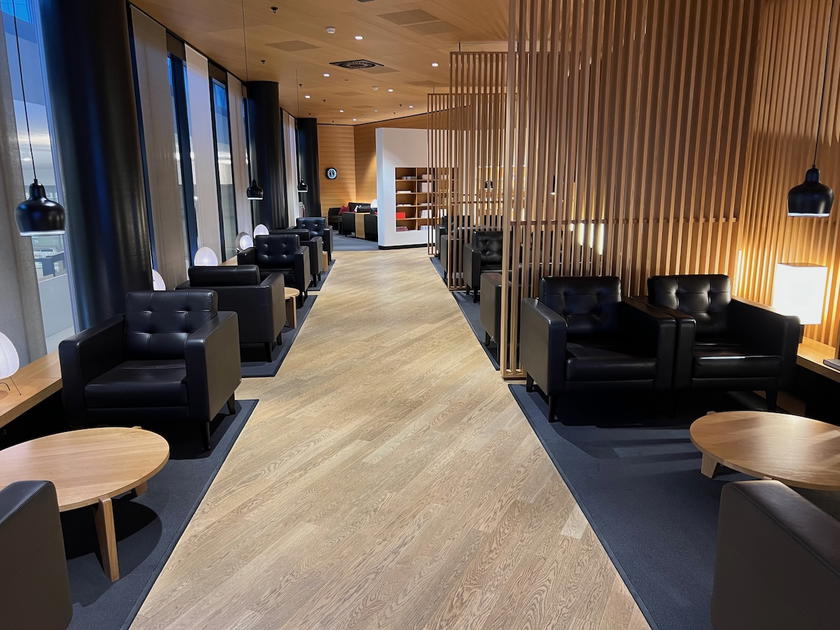 Black leather lounge chairs separated by wooden panels in the SWISS First Lounge Zurich Terminal A