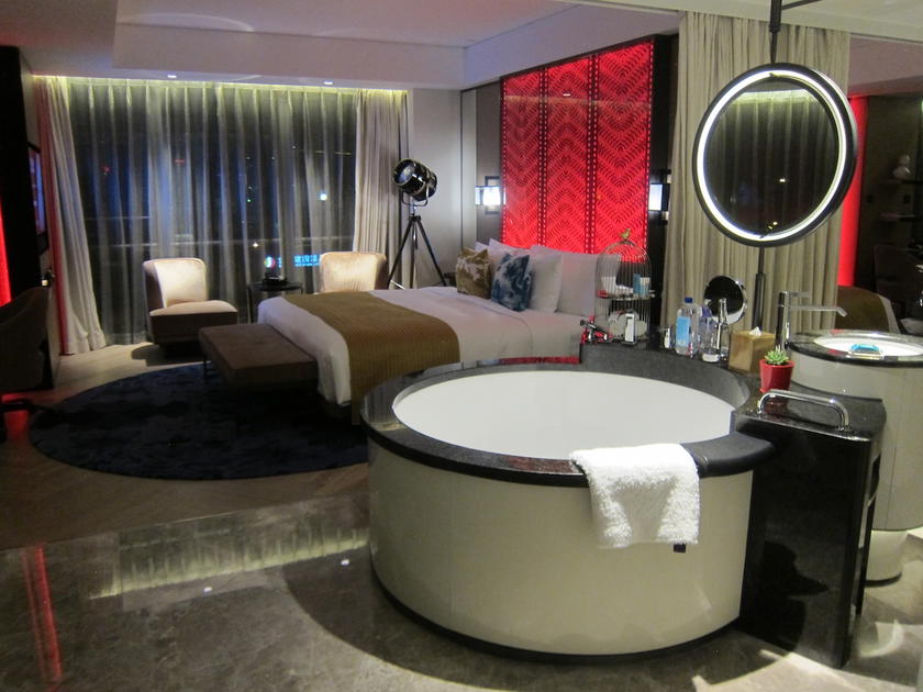Open hotel bathroom design with glass shower and tub visible from the bedroom at W Beijing