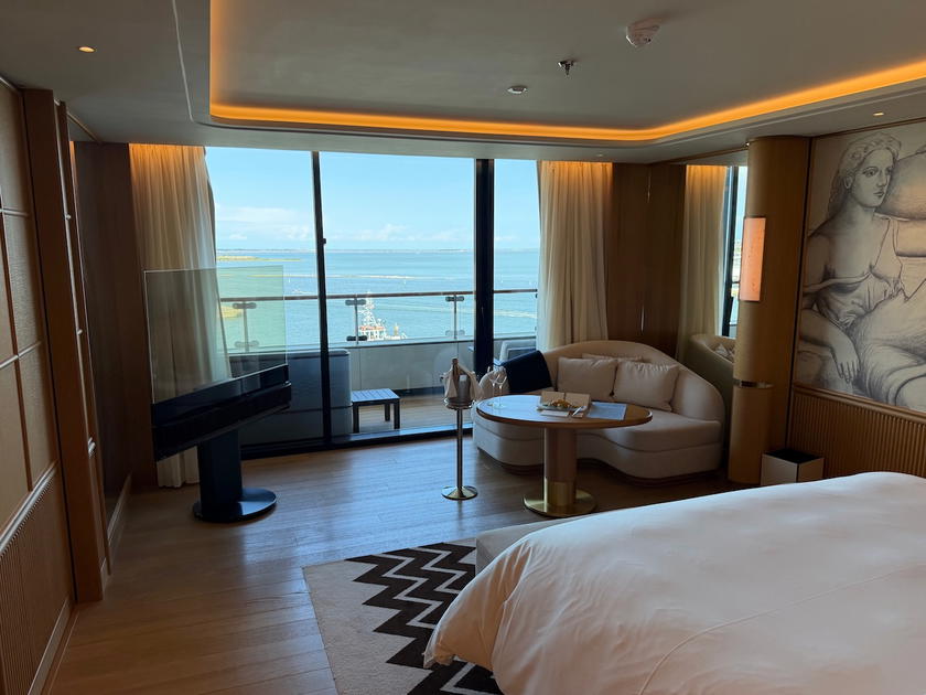 Bedroom in a Four Seasons Yachts suite with bed, seating area, and TV