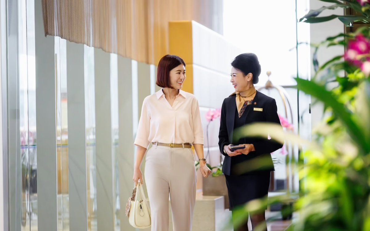Singapore Airlines concierge escorting a first class passenger through Changi Airport toward the lounge