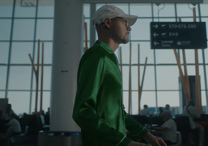 Man in green clothing walking through terminal near a map of Africa in Air Canada teaser video