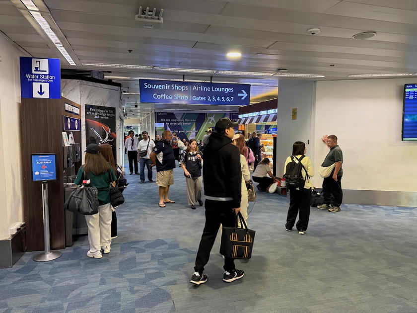 Small, easy-to-miss signage pointing toward airline lounges in the Manila Airport concourse
