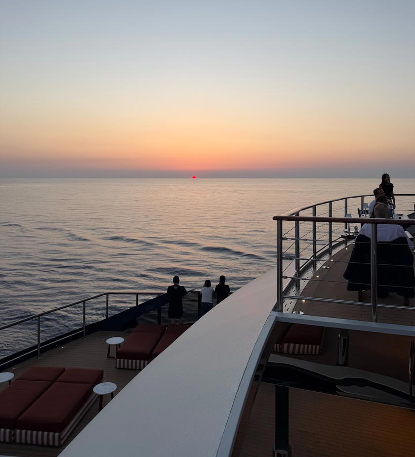 Guests gathered on Orient Express Corinthian's flybridge for a sail-away drink at sunset