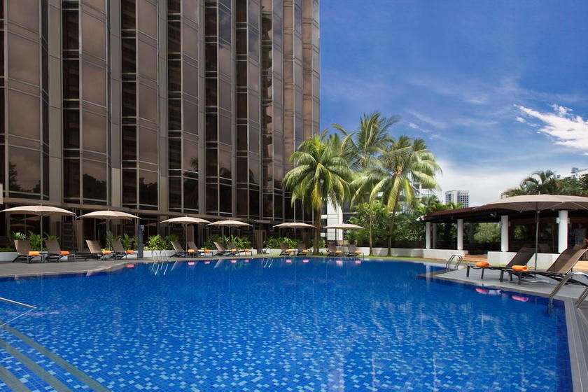 Outdoor pool area at the Sheraton Towers Singapore surrounded by palm trees and lounge chairs