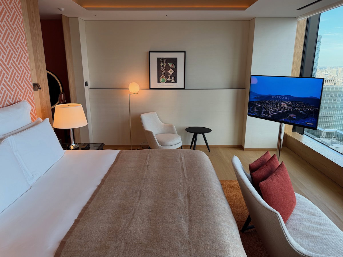 Desk area with a stool and a loveseat at the foot of the bed