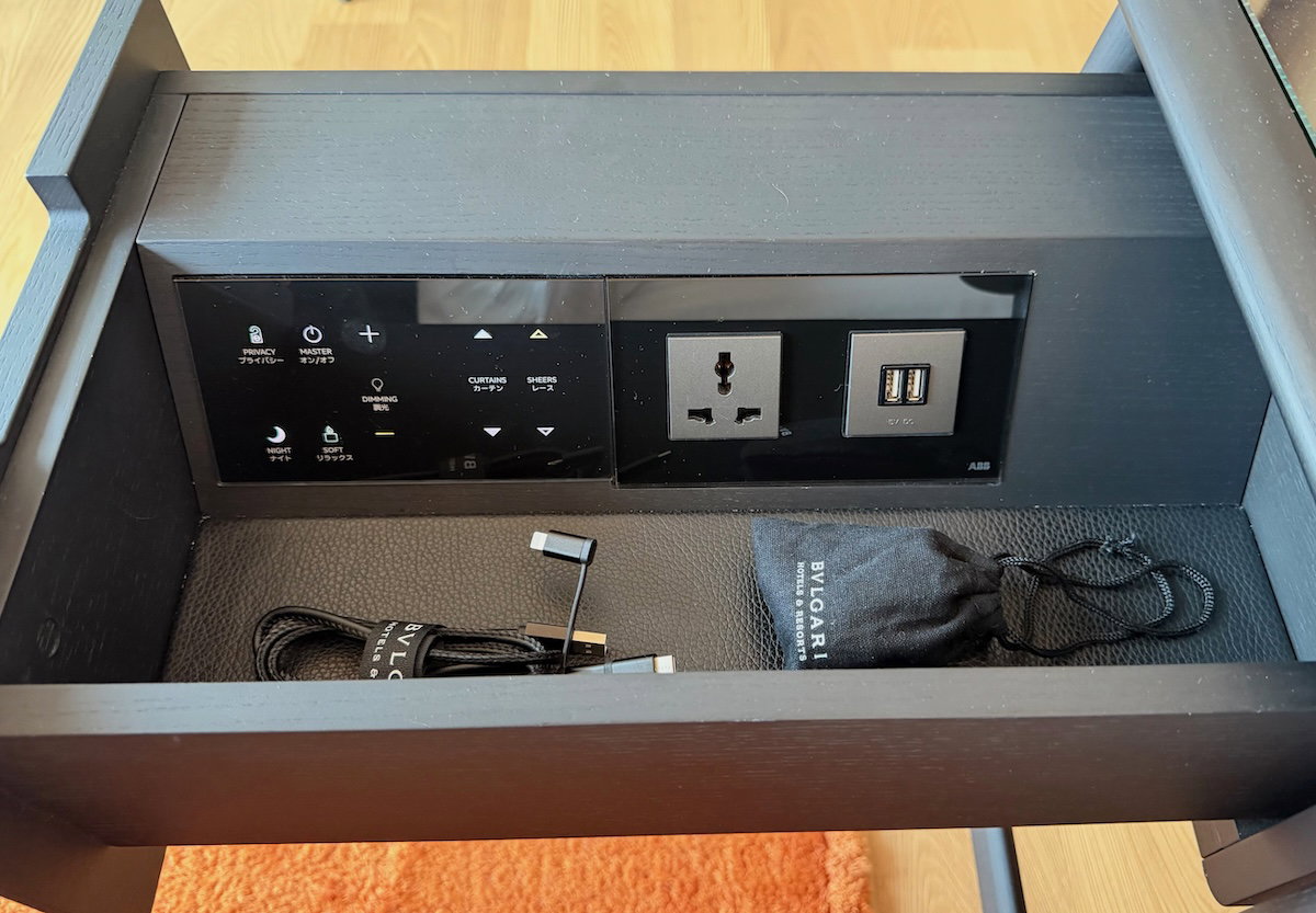 Bedside drawer concealing power outlets and room controls