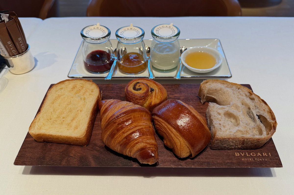 Basket of croissants and pastries served with jam and yogurt at breakfast