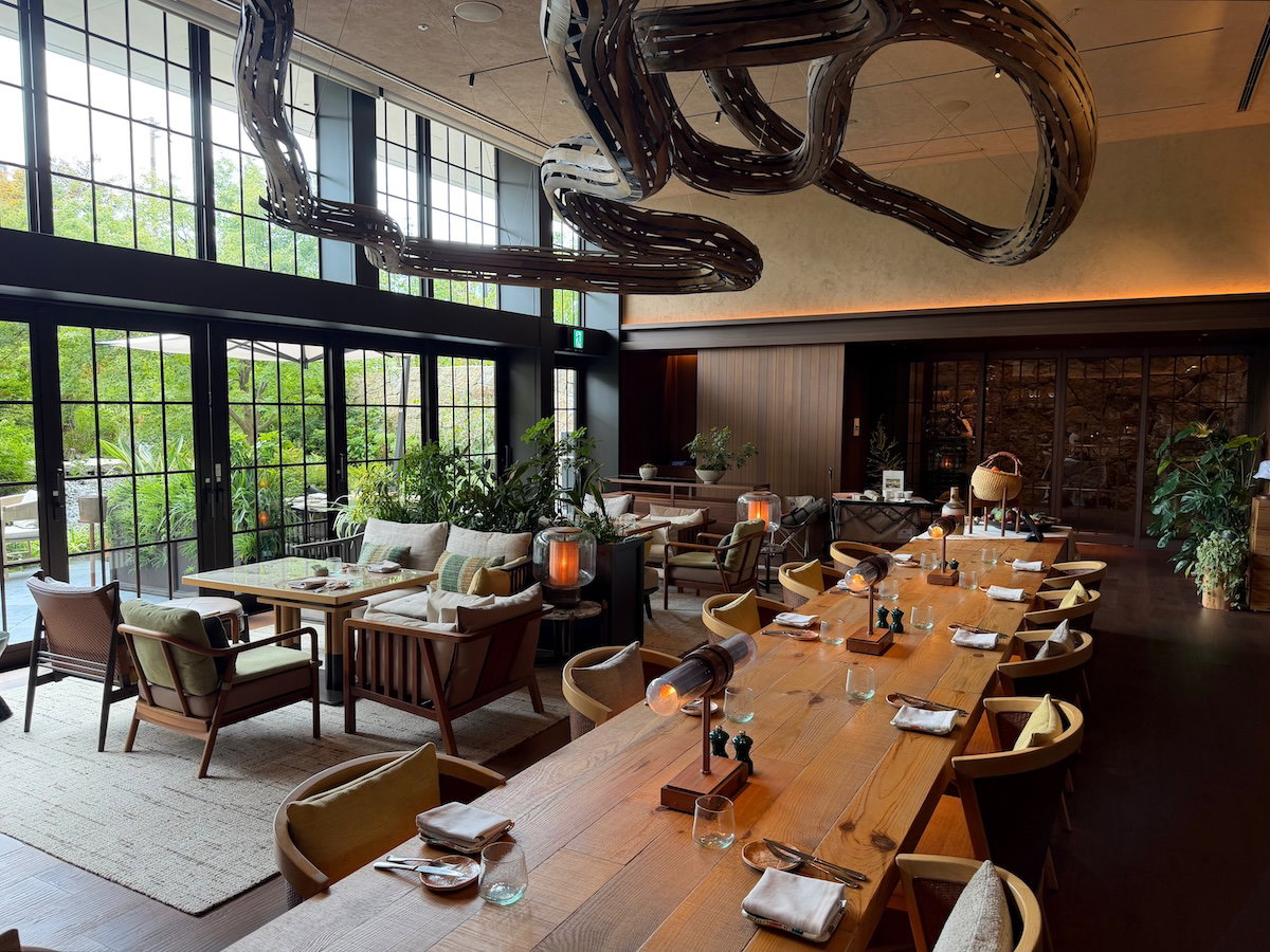 Tables and greenery inside the P72 restaurant at Patina Osaka