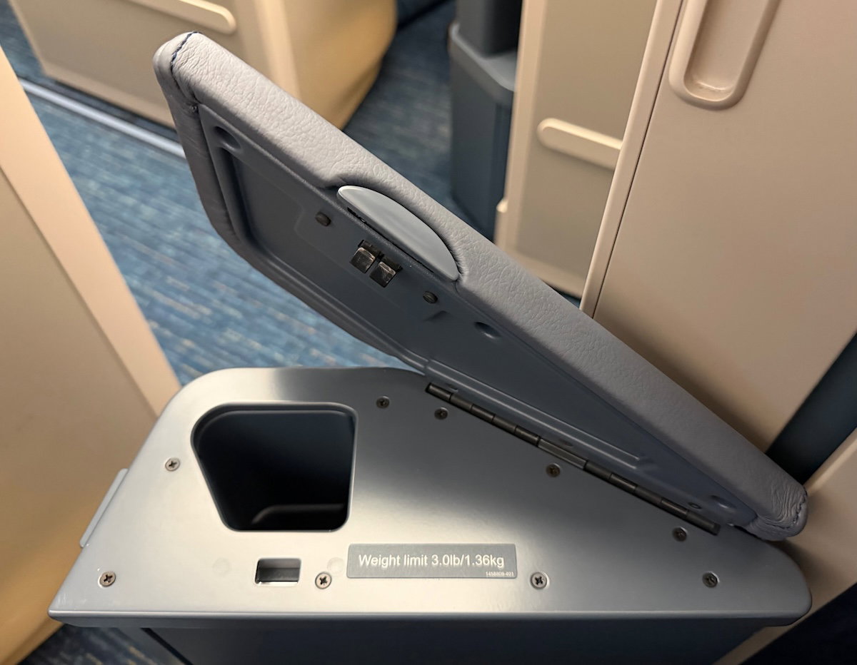 Aisle-side armrest opened to show a small storage space for a water bottle
