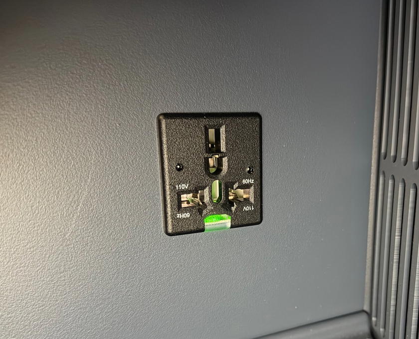 AC power outlet tucked underneath the side of the business class seat