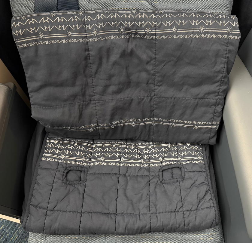 Pillow, blanket and mattress pad laid out on a Philippine Airlines business class seat