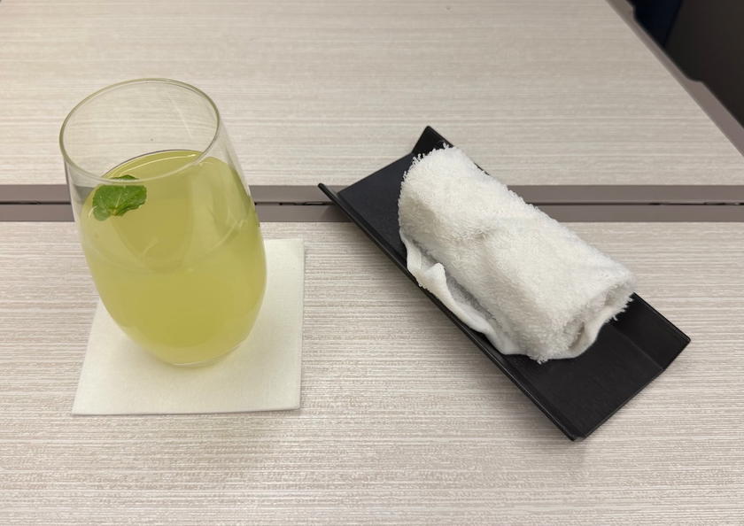 Cucumber iced tea pre-departure drink served with a warm towel in business class