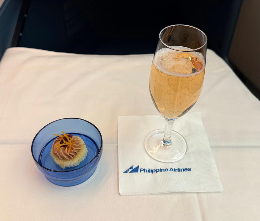 Glass of champagne with a chicken liver pate amuse bouche on a tray table